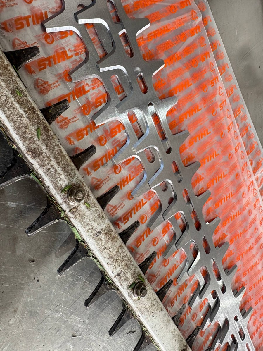 Messerbalken einer Heckenschere neben einem Ersatzmesser in STIHL-Verpackung