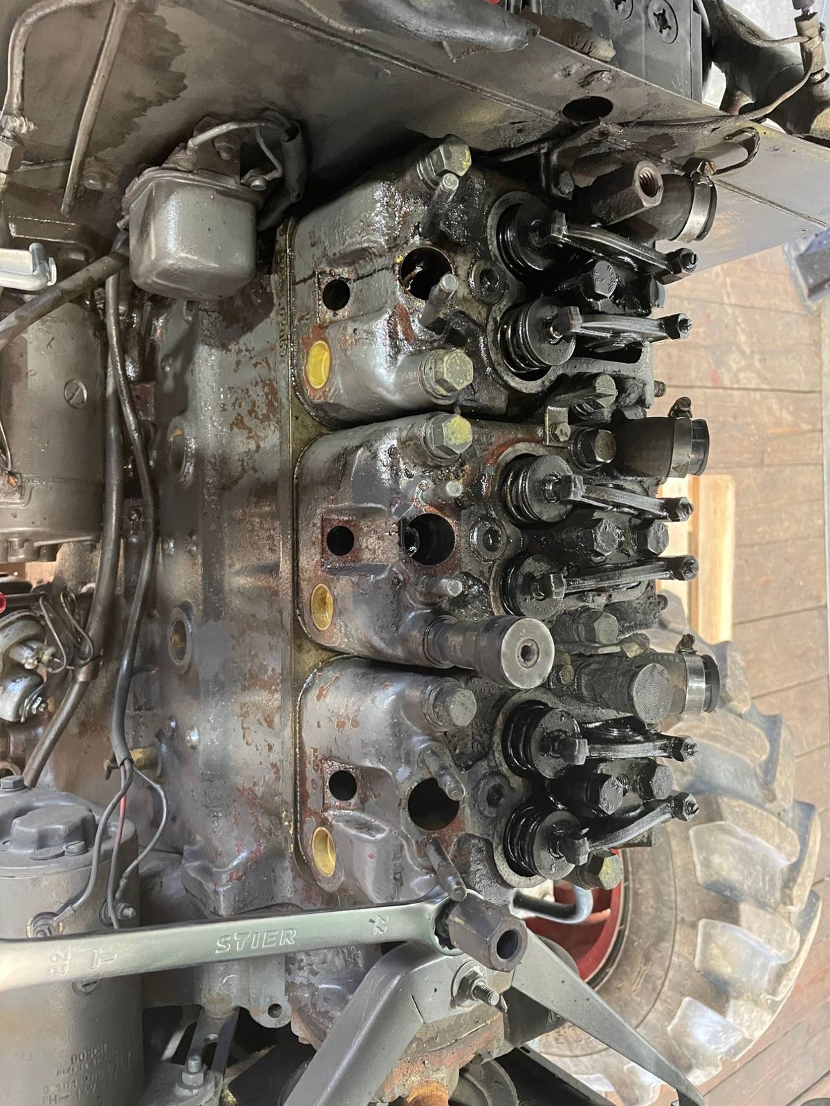 Geöffneter Dreizylinder-Dieselmotor eines Traktors mit freigelegten Zylinderköpfen, Ventilen und Einspritzdüsen