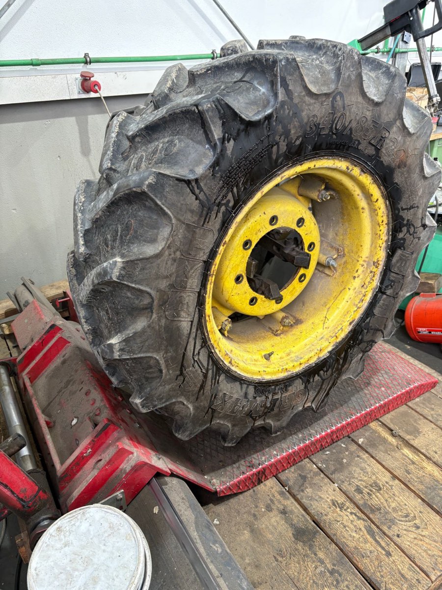 Großer Traktorreifen 340/85 R24 auf gelber Felge in der Reifenmontiermaschine